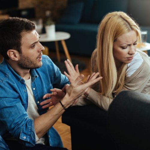 Couple with relationship difficulties having a conflict while talking in the living room.