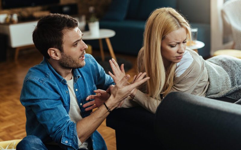 Couple with relationship difficulties having a conflict while talking in the living room.