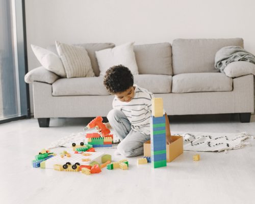 Child play games on floor. African kid make up a constructor. Curly hair in a boy.