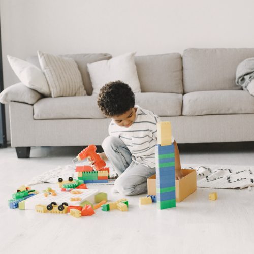 Child play games on floor. African kid make up a constructor. Curly hair in a boy.