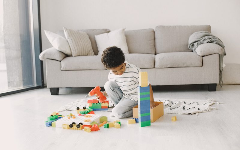 Child play games on floor. African kid make up a constructor. Curly hair in a boy.