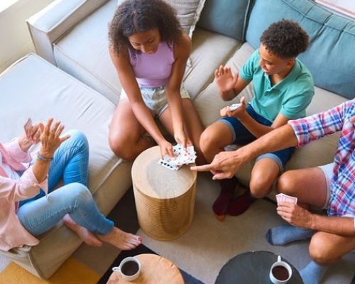 Overhead Shot Of Grandparents And Grandchildren At Home In Lounge Playing Game Of Cards Together