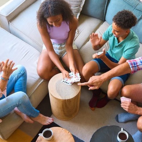 Overhead Shot Of Grandparents And Grandchildren At Home In Lounge Playing Game Of Cards Together