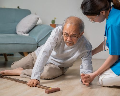 Asian older senior man falling down on lying floor and woman nurse came to help support, Disabled elderly old man patient fall down and caring young assistant at nursing home