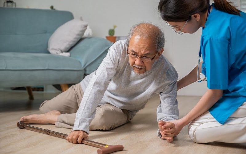 Asian older senior man falling down on lying floor and woman nurse came to help support, Disabled elderly old man patient fall down and caring young assistant at nursing home