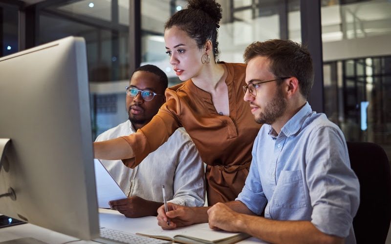 Learning, computer and training business interns in night office with manager, boss and leadership help. Men with technology planning ideas, kpi strategy and marketing innovation vision with mentor