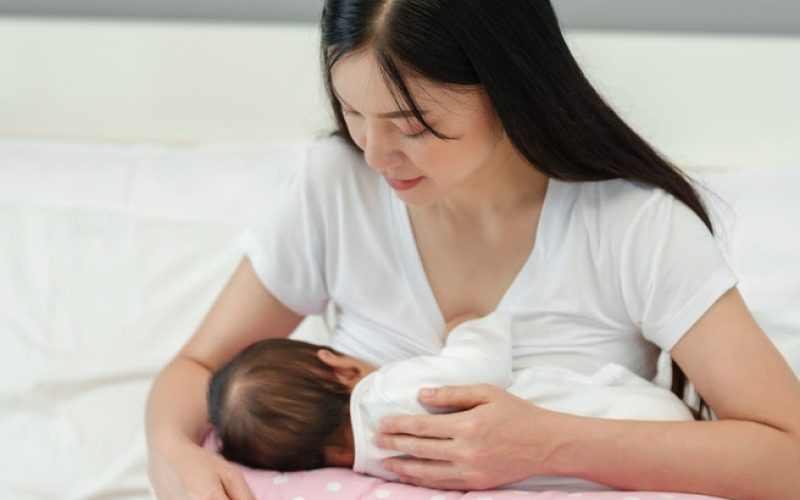 mother breastfeeding newborn baby on a support pillow cushion
