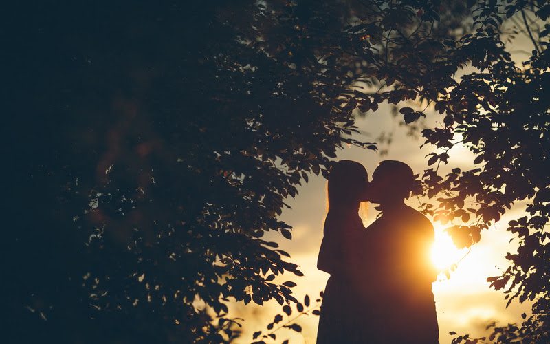 Romantic couple on sunset under the tree